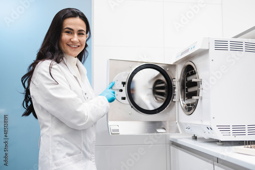 Medical worker in the instrument sterilization room. Doctor assistant working with autoclave photo