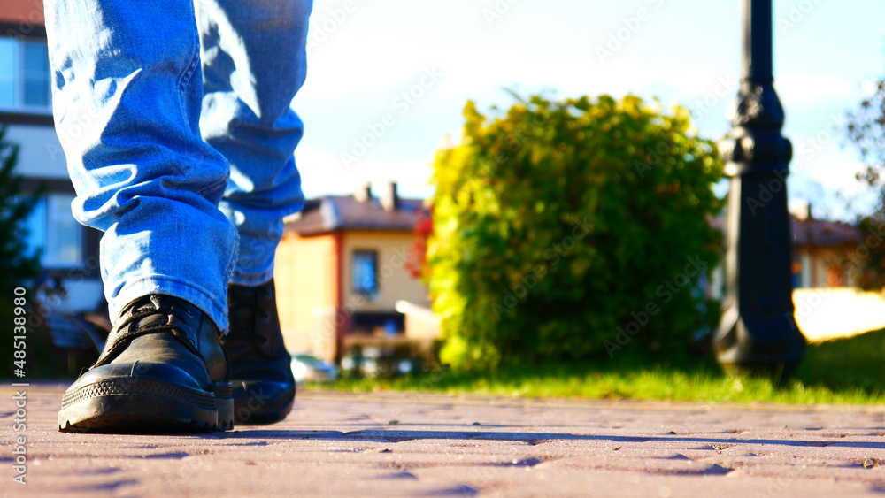 One man in black shoes walks along a beautiful sidewalk One man in black shoes walks along a beautiful sidewalk