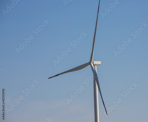 wind mill or also wind-turbine on wind farm in rotation to generate electricity energy on outdoor with sun and blue sky, conservation and sustainable energy concept © Oleh Marchak