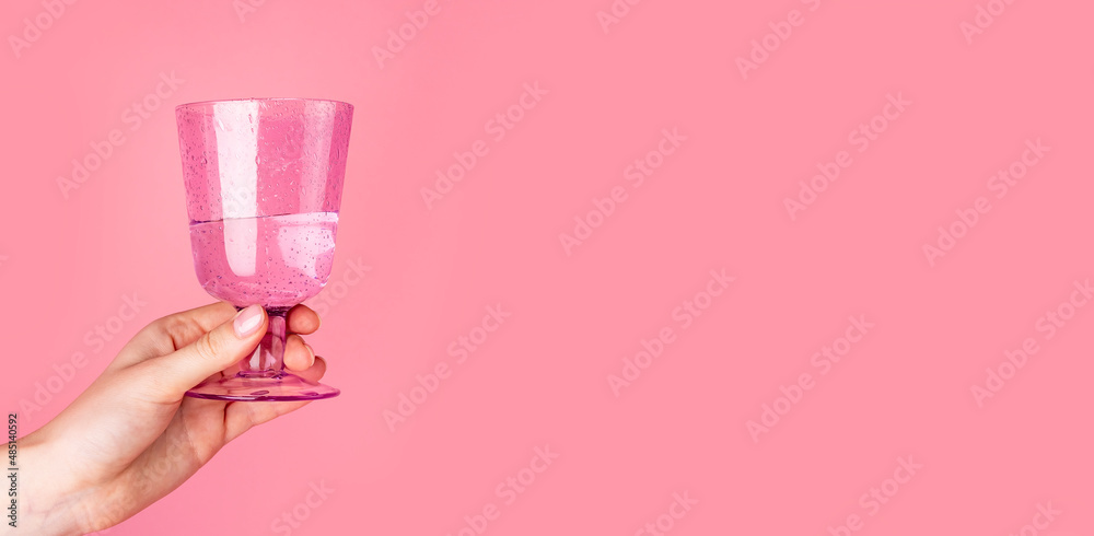 Banner with woman hand holding glass on pink background. Valentines day concept. Copy space. High quality photo