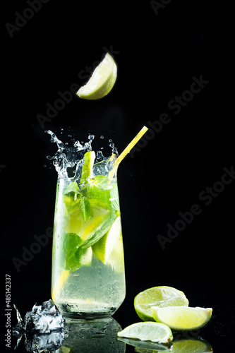 A slice of lime falling into a glass. A piece of lemon falling into a cocktail. A piece of lemon in the air.