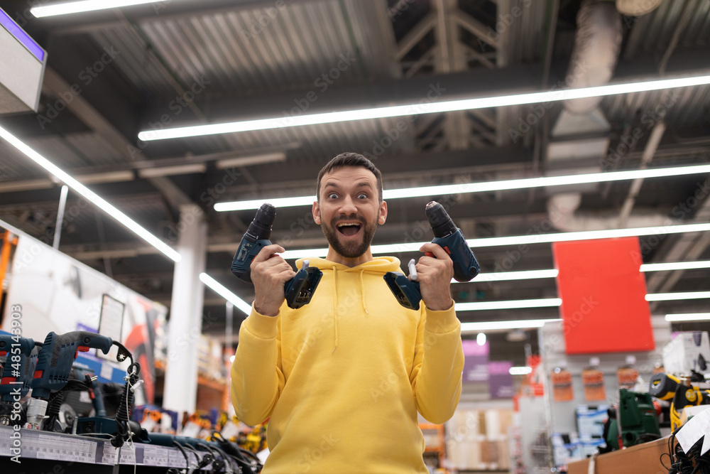 happy and cheerful customer with two screwdriver and in his hands in a hardware store happy and cheerful customer with two screwdriver and in his hands in a hardware store