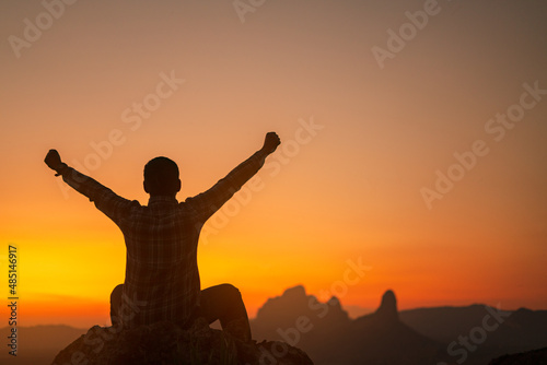 Silhouette of success man hiker outstretched arms on top of the mountain with beautiful sunset.Concept of adventure travel