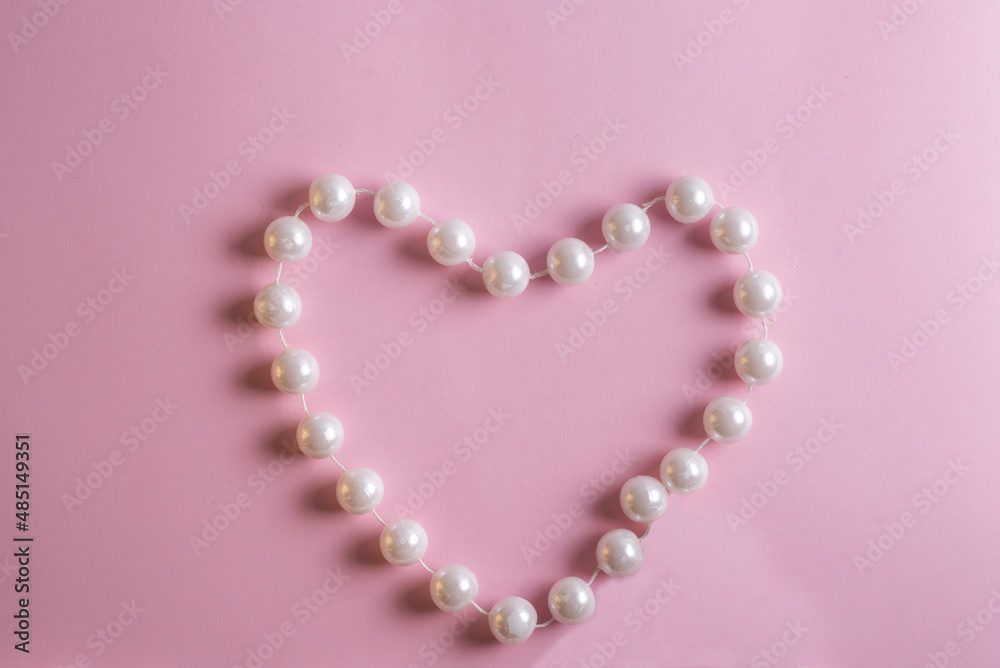 Obraz premium frame in the form of a heart made of pearls on a pink background with a place for an inscription