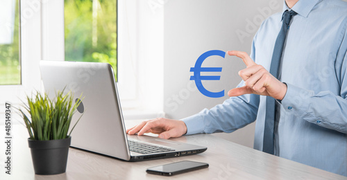 Businessman holds money coin icons EUR or Euro on dark tone background..Growing money concept for business investment and finance
