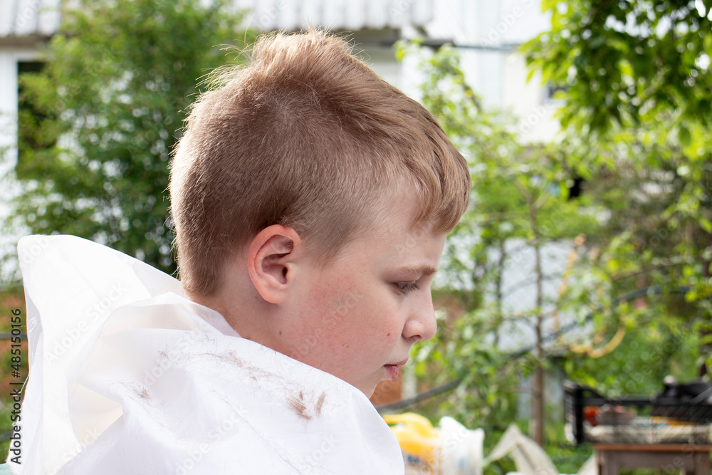 Obraz premium girl cuts the boy's hair with a clipper