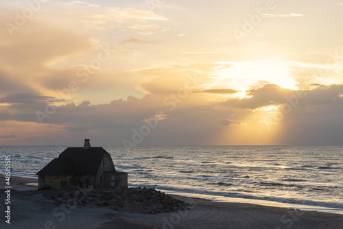 Lonely beach house with dramatic sky by the sea.  photo