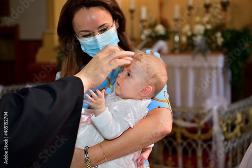 Fototapeta The pastor baptizes a child in the church using holy water