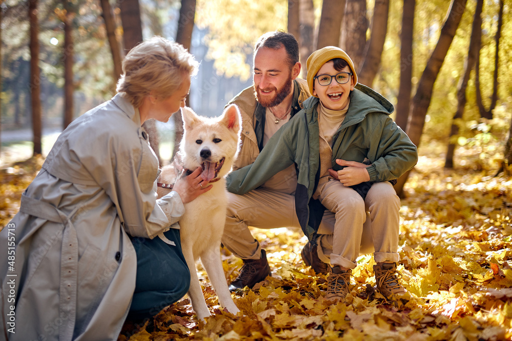 excited family with dog on walk in autumn park. family, pet, domestic animal and people concept. young man, woman and child boy in coats outdoors on warm weather. human emotions concept excited family with dog on walk in autumn park. family, pet, domestic animal and people concept. young man, woman and child boy in coats outdoors on warm weather. human emotions concept