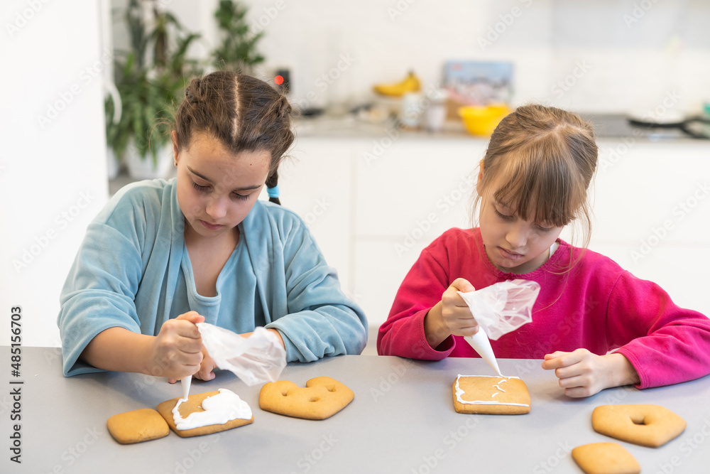 Portrait of happy small children decorating homemade cookies in kitchen and making xmas cookies together at home Portrait of happy small children decorating homemade cookies in kitchen and making xmas cookies together at home
