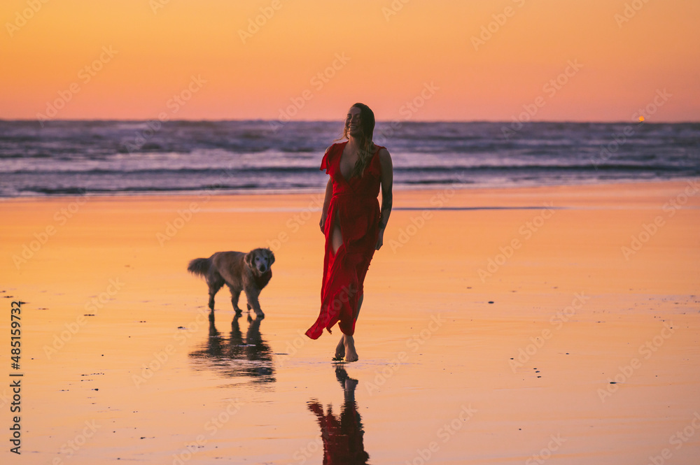 Female wearing a red dress on the Washington Coast at sunset Female wearing a red dress on the Washington Coast at sunset