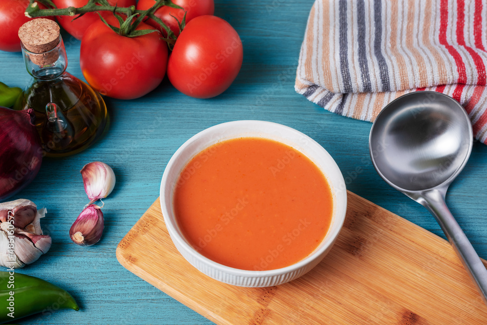Gazpacho, cold soup typical of Andalusia based on tomato, garlic, pepper and onion. On a blue wooden background. Gazpacho, cold soup typical of Andalusia based on tomato, garlic, pepper and onion. On a blue wooden background.