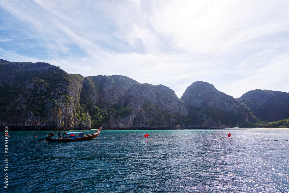 Travel by Thailand. Beautiful tropical lanscape with traditional lontail boat sailing the sea with famous Maya Bay on the background.