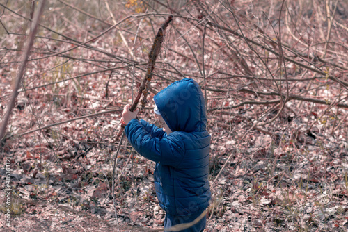 A little boy makes his way through the thickets in the forest