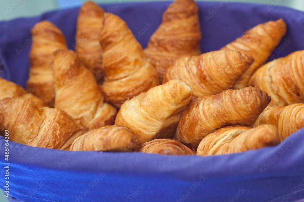 Fresh croissants and bakery arranged in a basket with a red material for protection