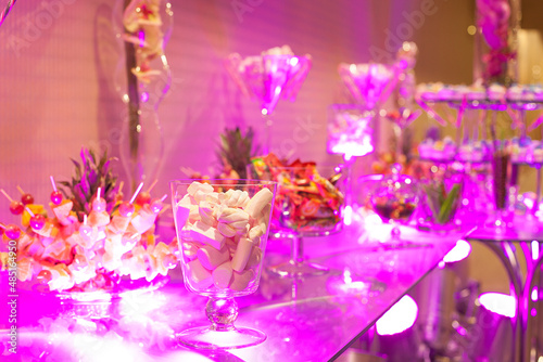 Candy bar, table with sweets, delicious sweet cupcakes lie on a glass plate on a table with lights © marindumitru