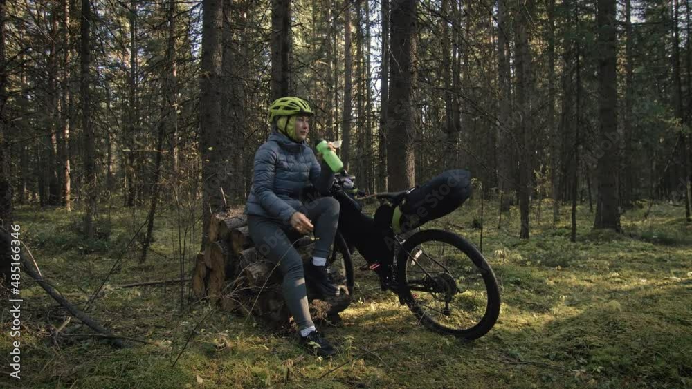 The woman travel on mixed terrain cycle touring with bike bikepacking. The traveler journey with bicycle bags. Magic forest park.