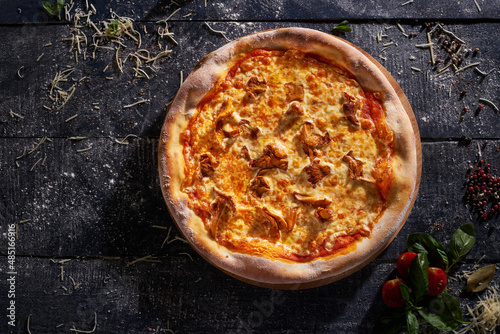 Pizza with chanterelles isolated on dark wooden background top view