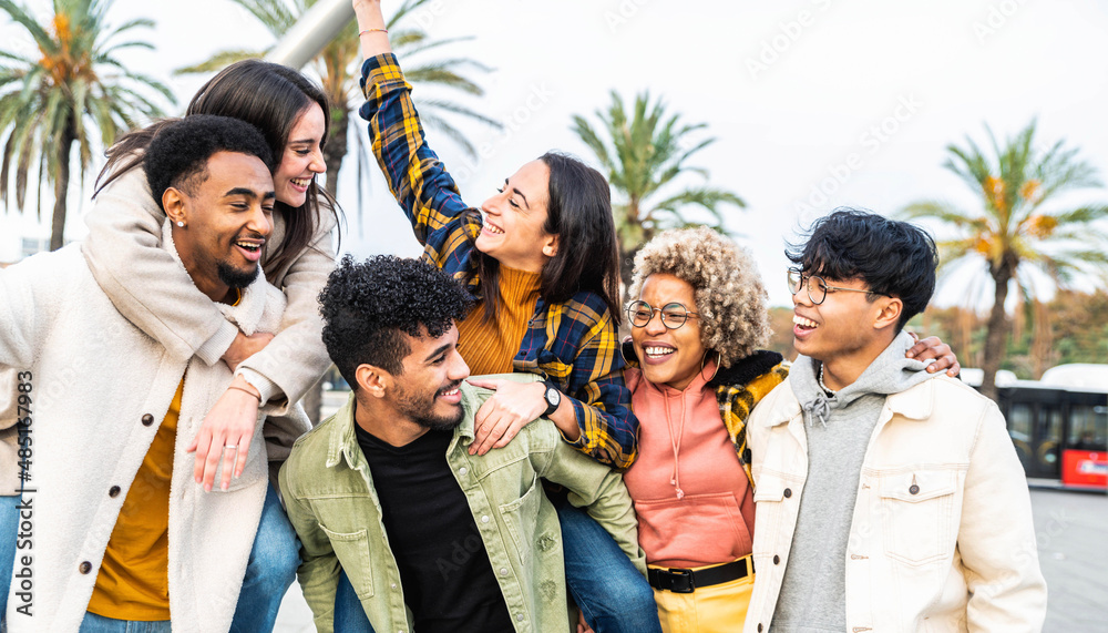 Obraz premium Multiracial group of friends bonding outside - Happy young people walking down the street laughing and having fun - Adult students hangout together in the city center - Friendship lifestyle concept