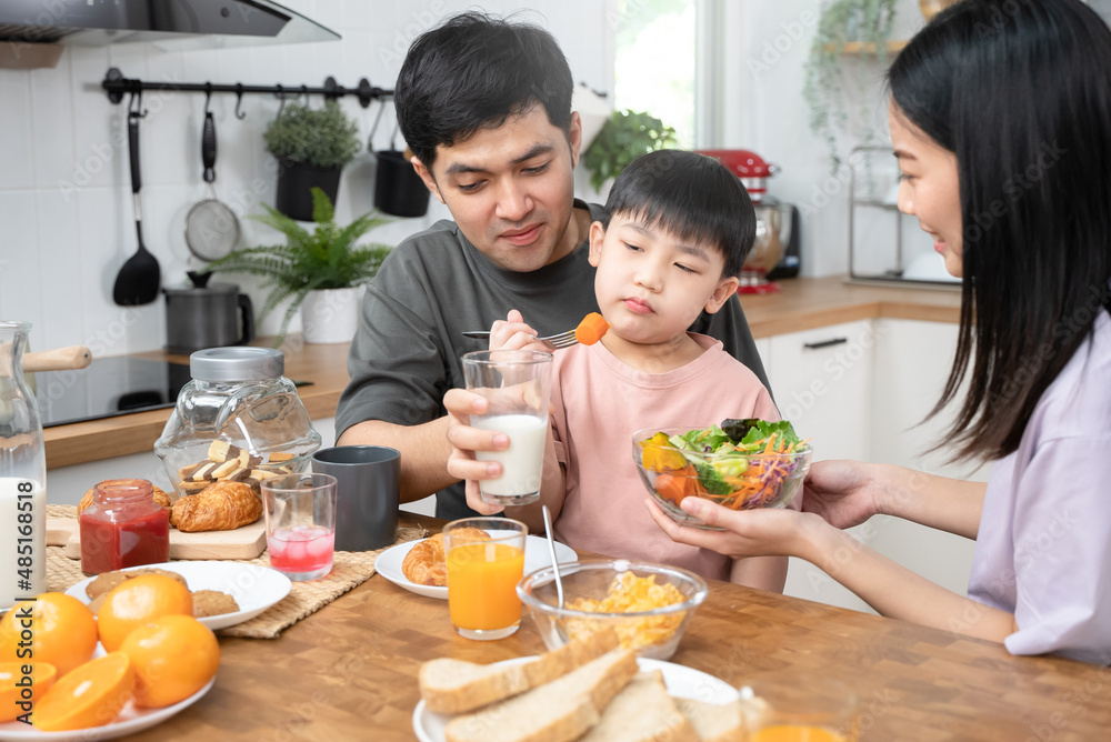 happy family together. Asian parent eating breakfast with little son in the kitchen. happy family together. Asian parent eating breakfast with little son in the kitchen.