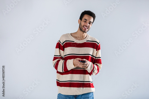 A young African American man with a smartphone in his hands stands on a white background.