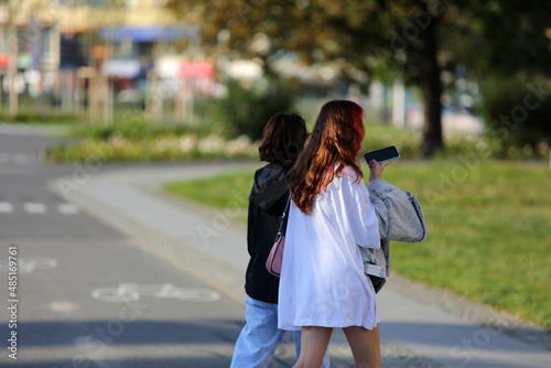 Dwie kobiety, dziewczyny z telefonem spacerują po chodniku, deptaku we Wrocławiu.	
 photo