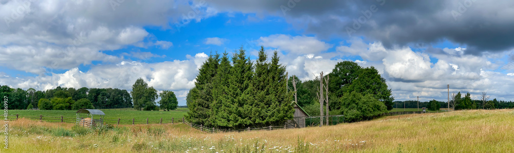 Panorama of beautiful Latvian rural landscape with flowering meadows in warm summer day with lush clouds on the sky. Panorama of beautiful Latvian rural landscape with flowering meadows in warm summer day with lush clouds on the sky.