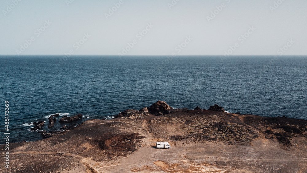 Camper van parked on the coast with blue sky and ocean water in ...