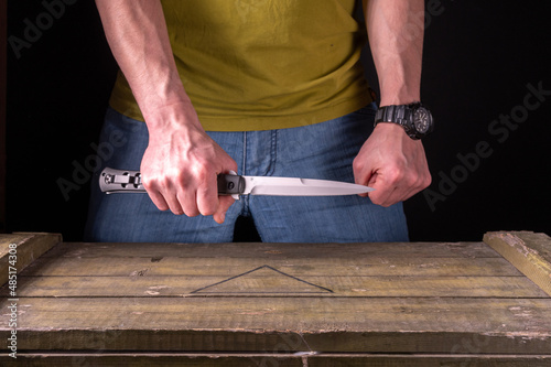 A large knife in the hands of a man. The man is holding a large knife. Sharp knife in hand.