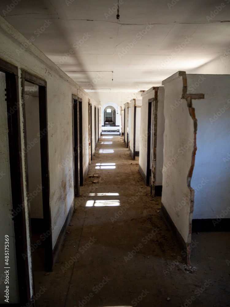 imagen de un pasillo con muchas puertas y la luz del sol entrando por la ventana en un edificio abandonado