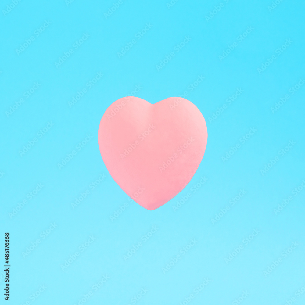 Pastel pink heart on a blue background. Minimal creative concept for Valentine's Day, love, tenderness, Mother's Day.