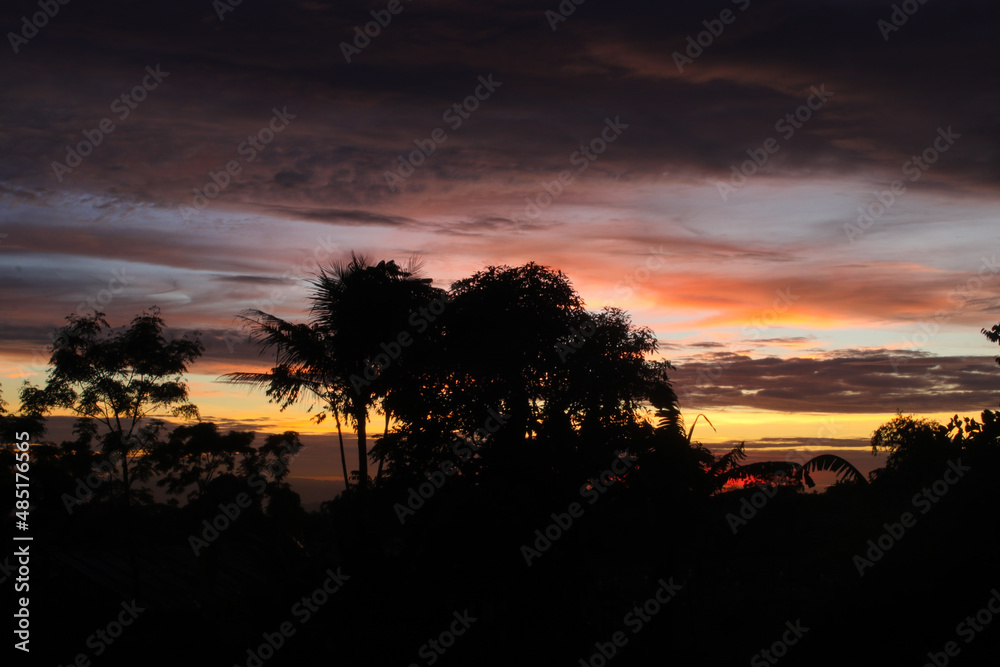 Beautiful dramatic afternoon sky with tree silhouette in a rural scene area. Dramatic sunset view in a village in Indonesia