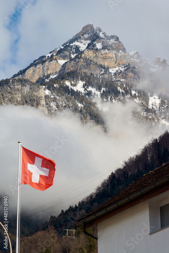 Flag of switzerland and  mountain covered with snow and clouds  in Switzerland in winter.