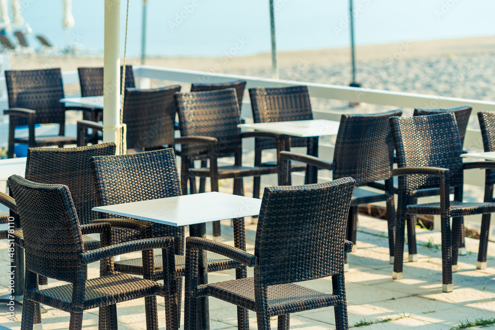 Range of wooden table and black chair for relaxation at restaurant near sea