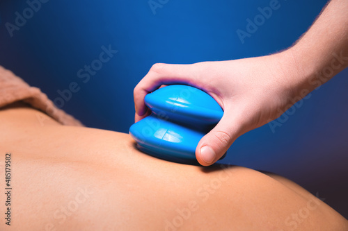 A man's hand places a vacuum rubber cup on the back of a male client