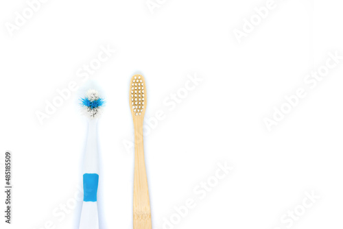 an eco-friendly bamboo toothbrush lies next to an old plastic brush on a white background. Flat lay  top view. Copy space. Zero waste personal care product  dental care