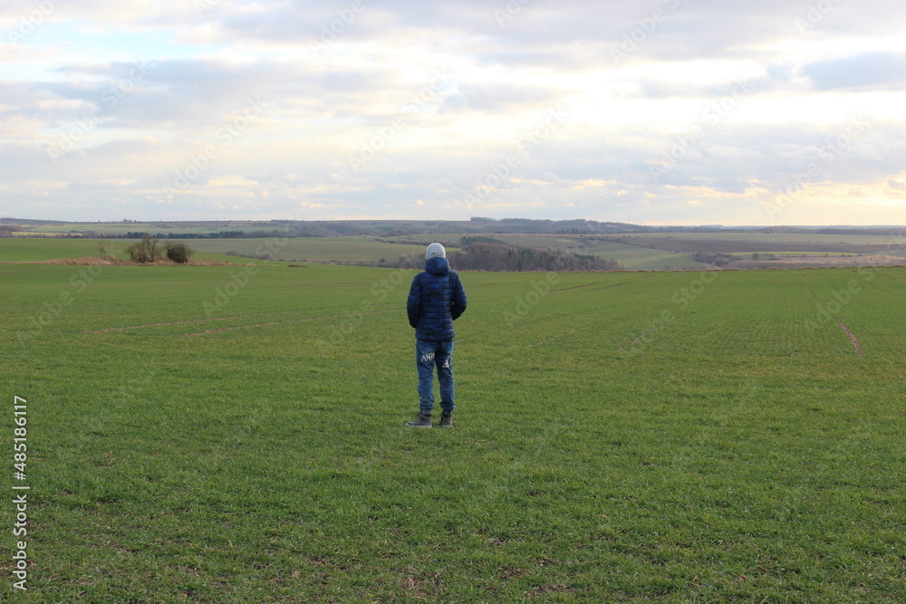 lonely young boy walking on a field