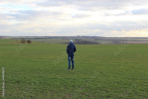 lonely young boy walking on a field