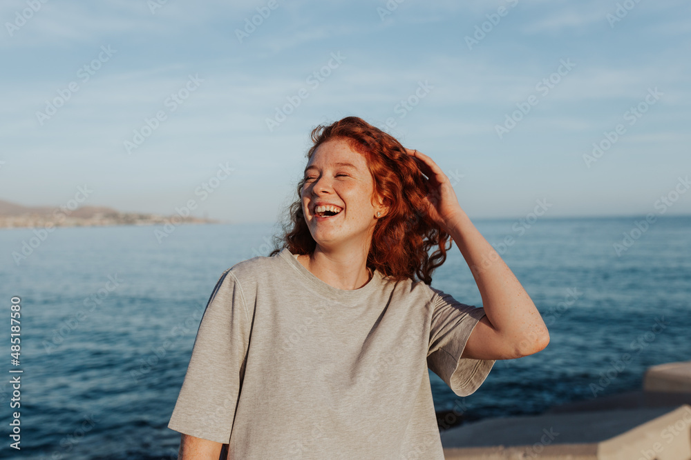 Happy young woman laughing cheerfully by the seaside Happy young woman laughing cheerfully by the seaside