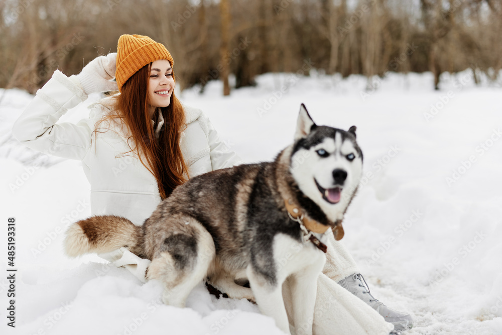 Naklejka premium Happy young woman outdoors in a field in winter walking with a dog Lifestyle