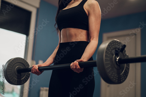Cropped shot of a female fitness instructor lifting barbell while training in the gym
