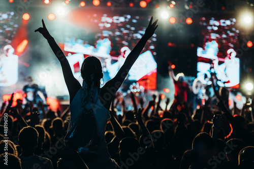 Obraz na plátně Silhouette of a woman with raised hands on a concert