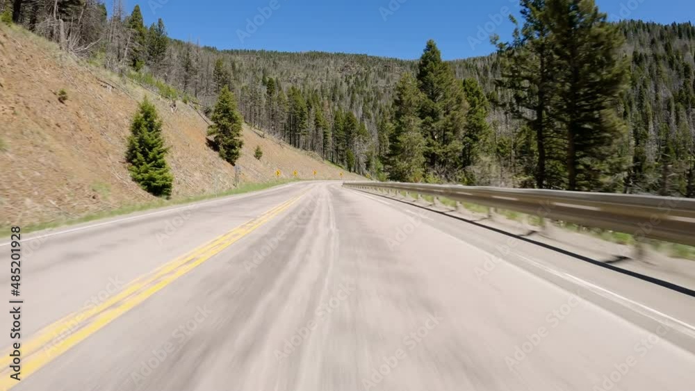 POV Driving a car going down on asphalt curvy road in Montana mountains. Sunny day with blue sky POV Driving a car going down on asphalt curvy road in Montana mountains. Sunny day with blue sky