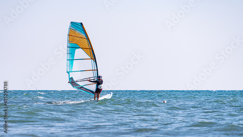 A man controls a sailboard at sea: one of the best remedies for a pandemic is windsurfing, and no mask is needed!