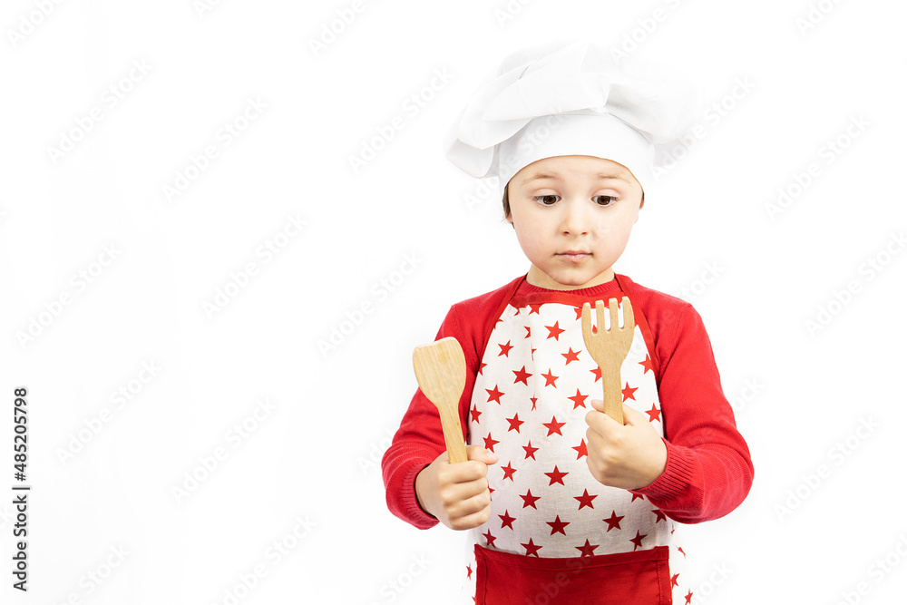 Child chef looking at kitchen utensils on white background Child chef looking at kitchen utensils on white background