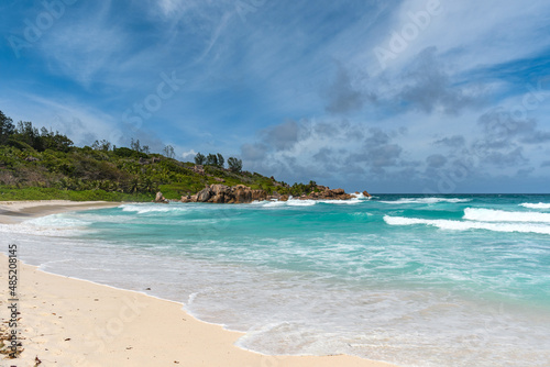 Idyllic sandy beach with turquoise sea and waves in the bay on a tropical island on Seychelles © Wirestock 