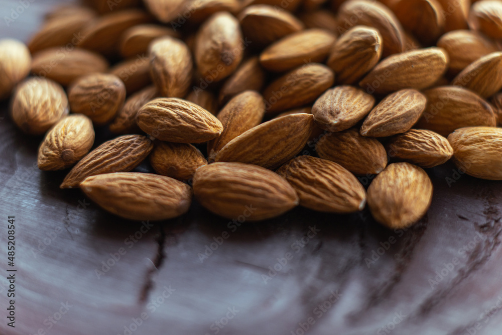 Close up almonds on dark wooden table. Organic health protein vegetarian food. Background copy space Close up almonds on dark wooden table. Organic health protein vegetarian food. Background copy space
