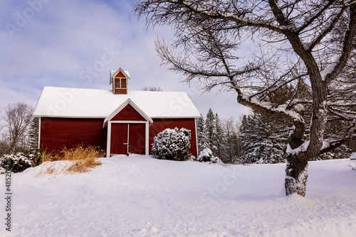 The village of Stanbrige-East, in the Eastern Townships, an old wooden barn painted red, with the land covered with snow. © santinovchphoto.com