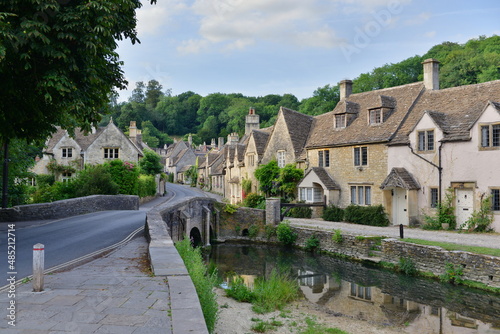 Scenic view of traditional old cottage houses by a river in a beautiful English village - namely the landmark village of Castle Combe in Wiltshire England