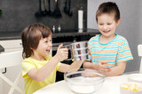 Children prepare dough in the kitchen. The boys cook at home. Time with children at home. Little chefs